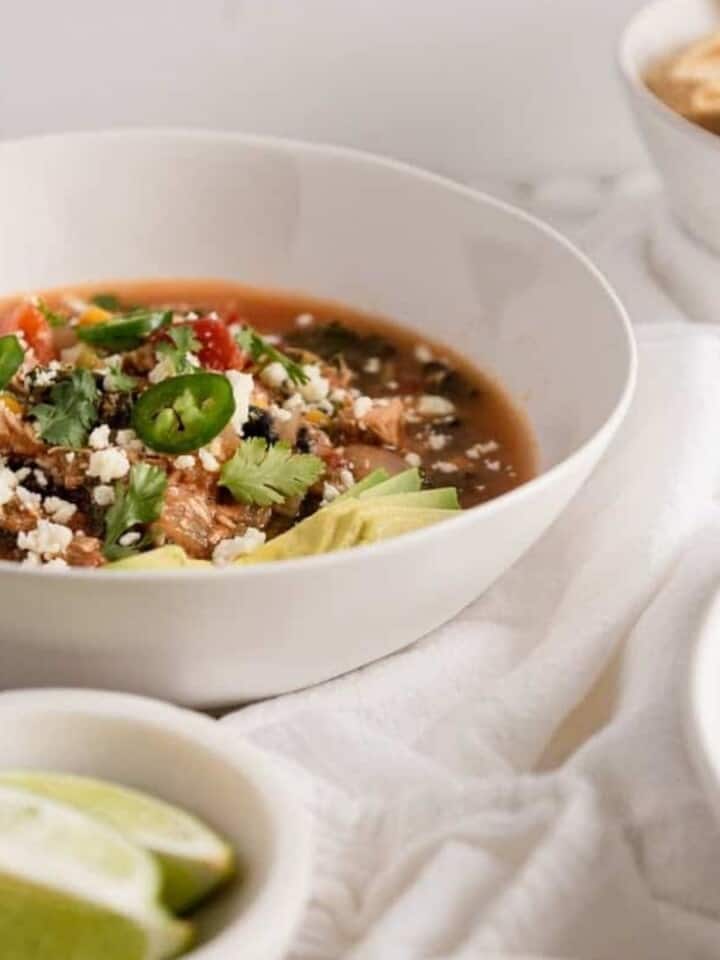 tortilla soup peaking out behind a bowl of limes