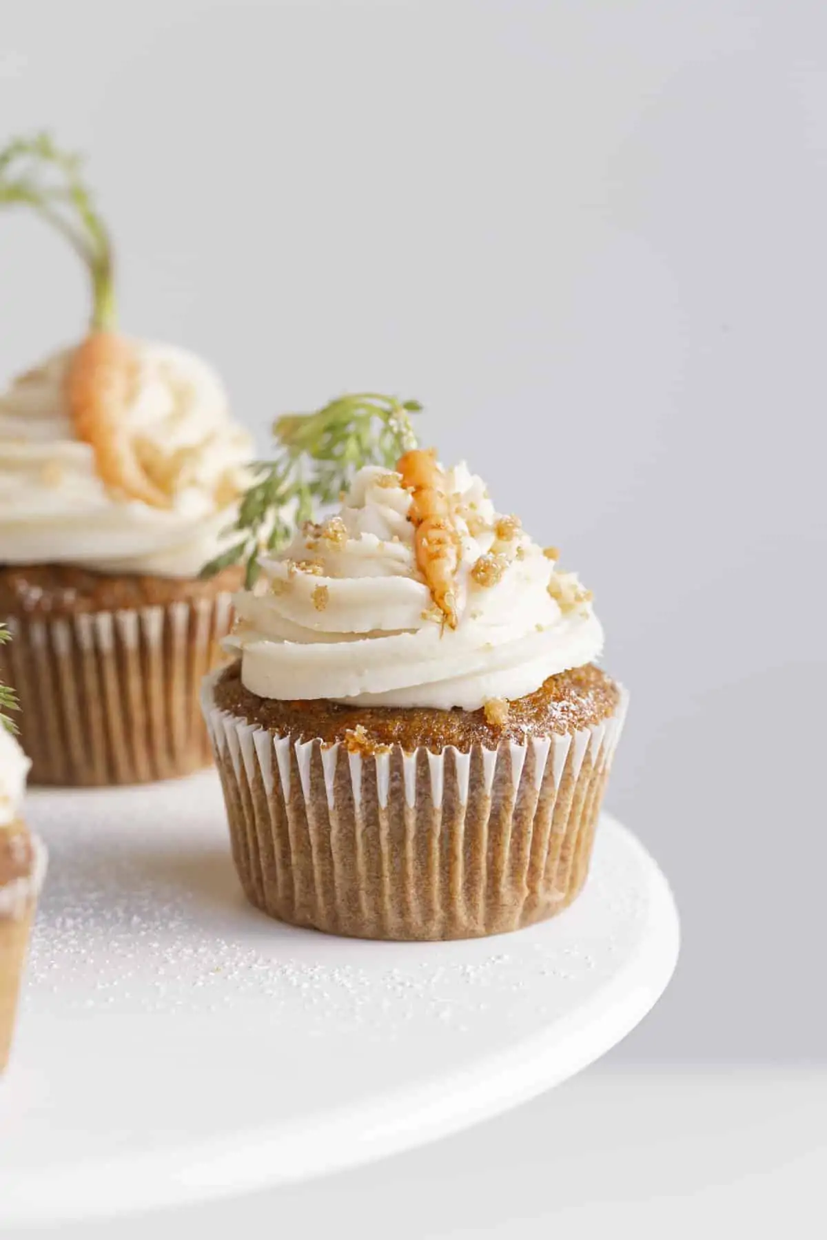 small batch carrot cake cupcakes on a stand with frosting