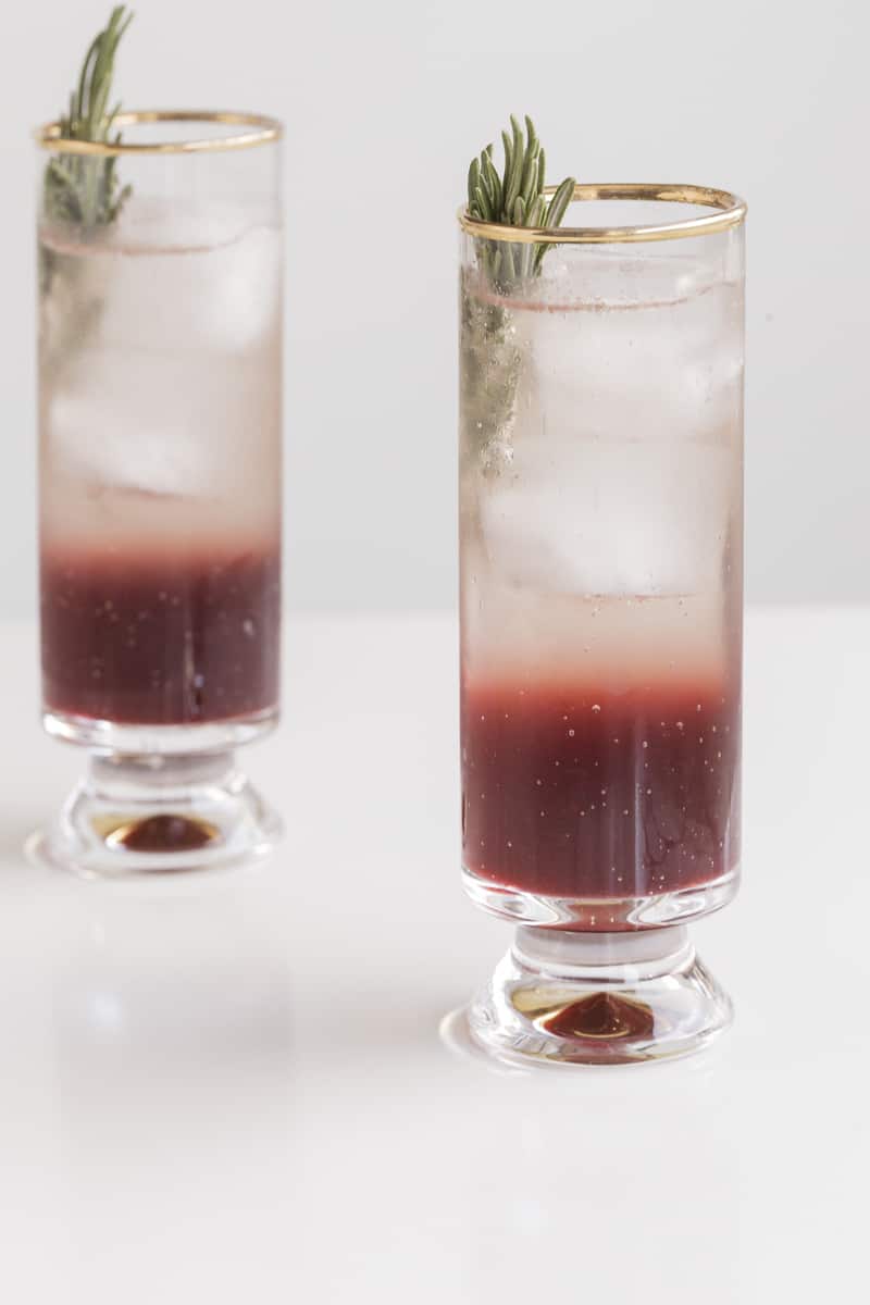 grape cocktail in two glasses with ice and rosemary