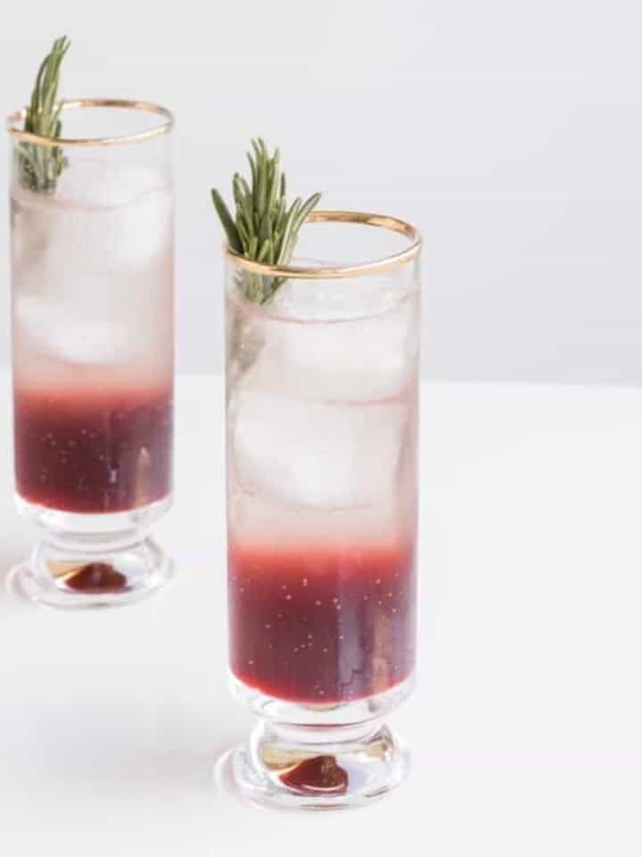 2 glasses with layered cocktail, ice, and rosemary