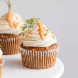 spiced carrot cupcakes on a stand with flowers and mini carrots