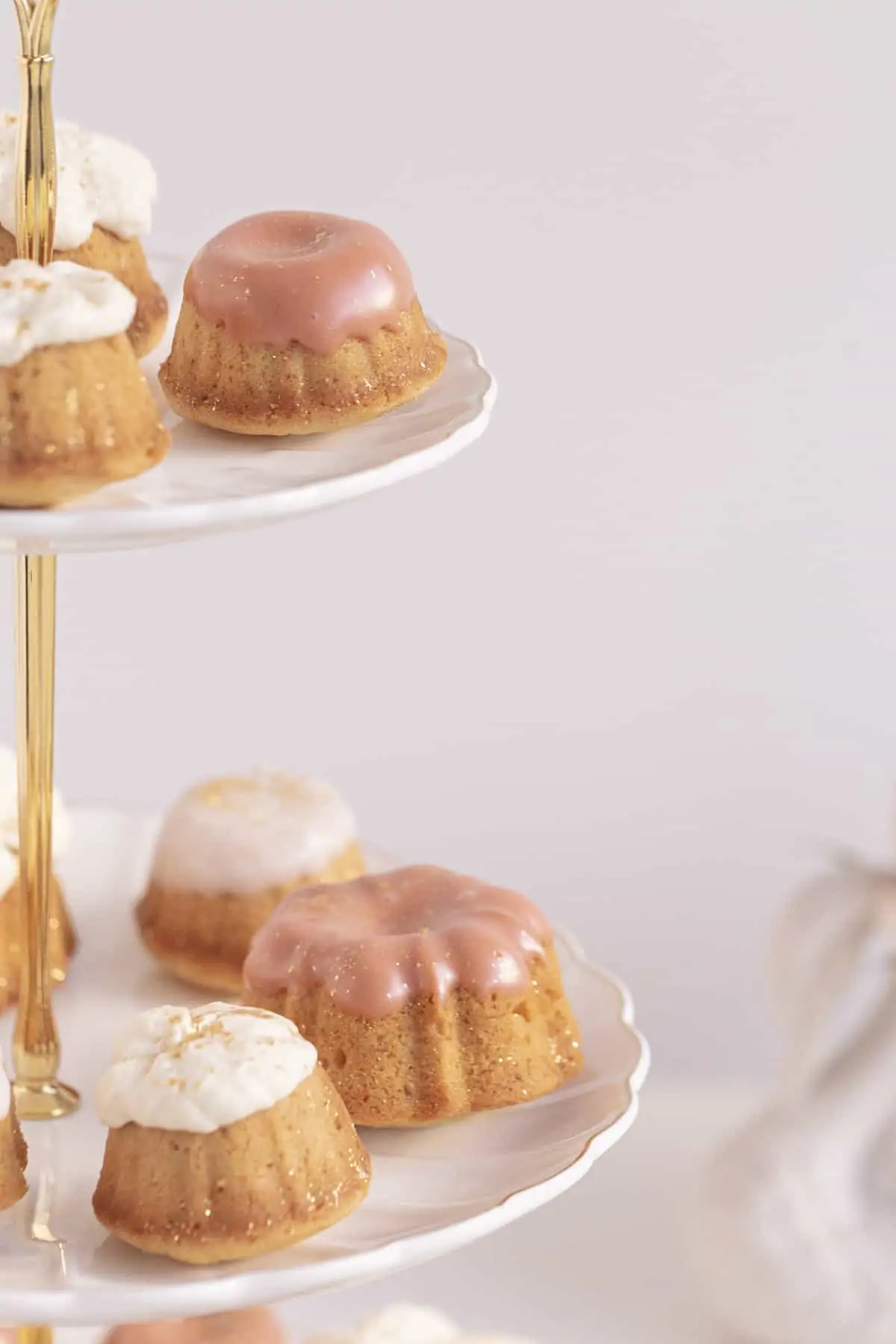 honey cakes on a cake stand with pink icing and whipped cream