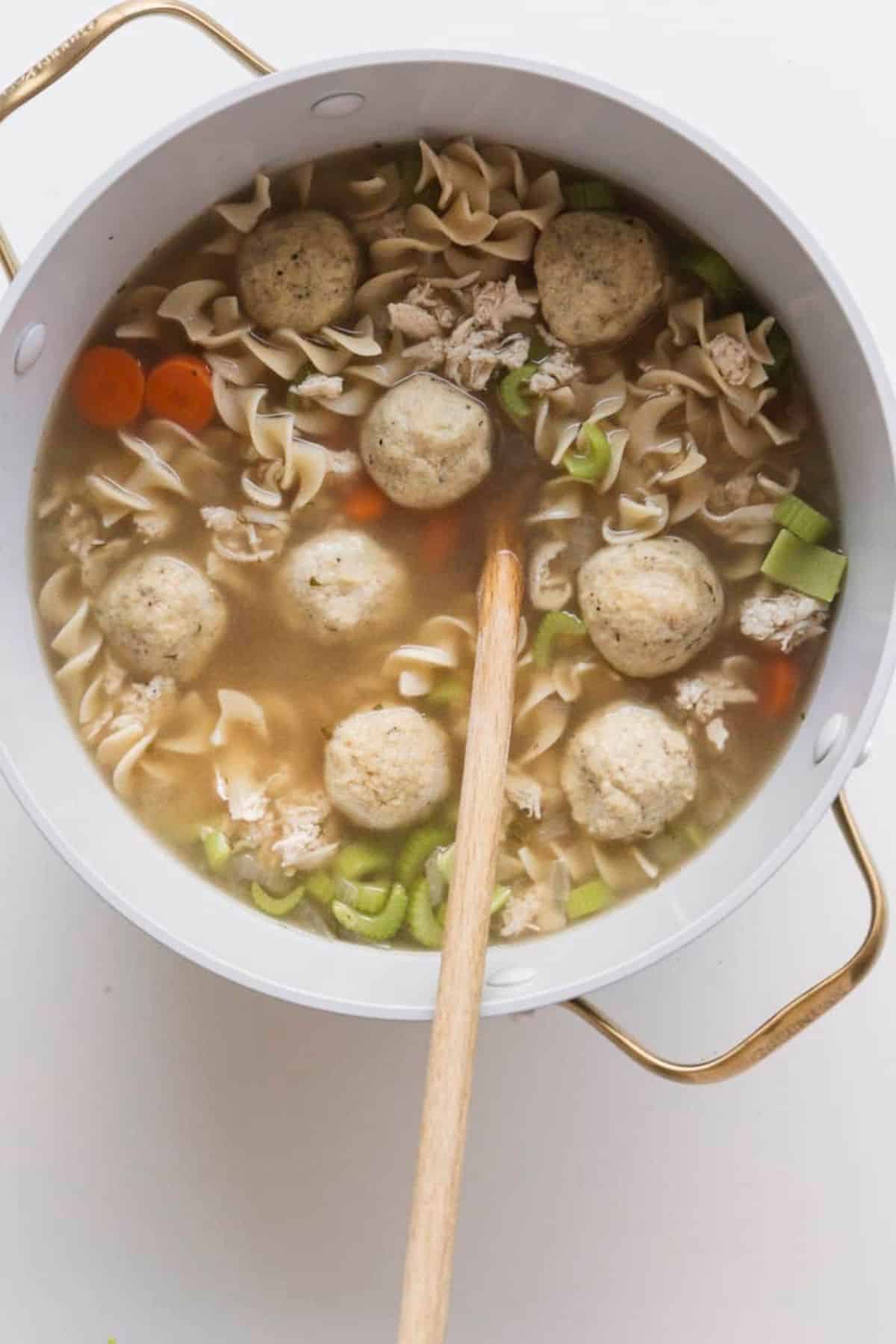 matzo ball soup with noodles and chicken in a pot with spoon