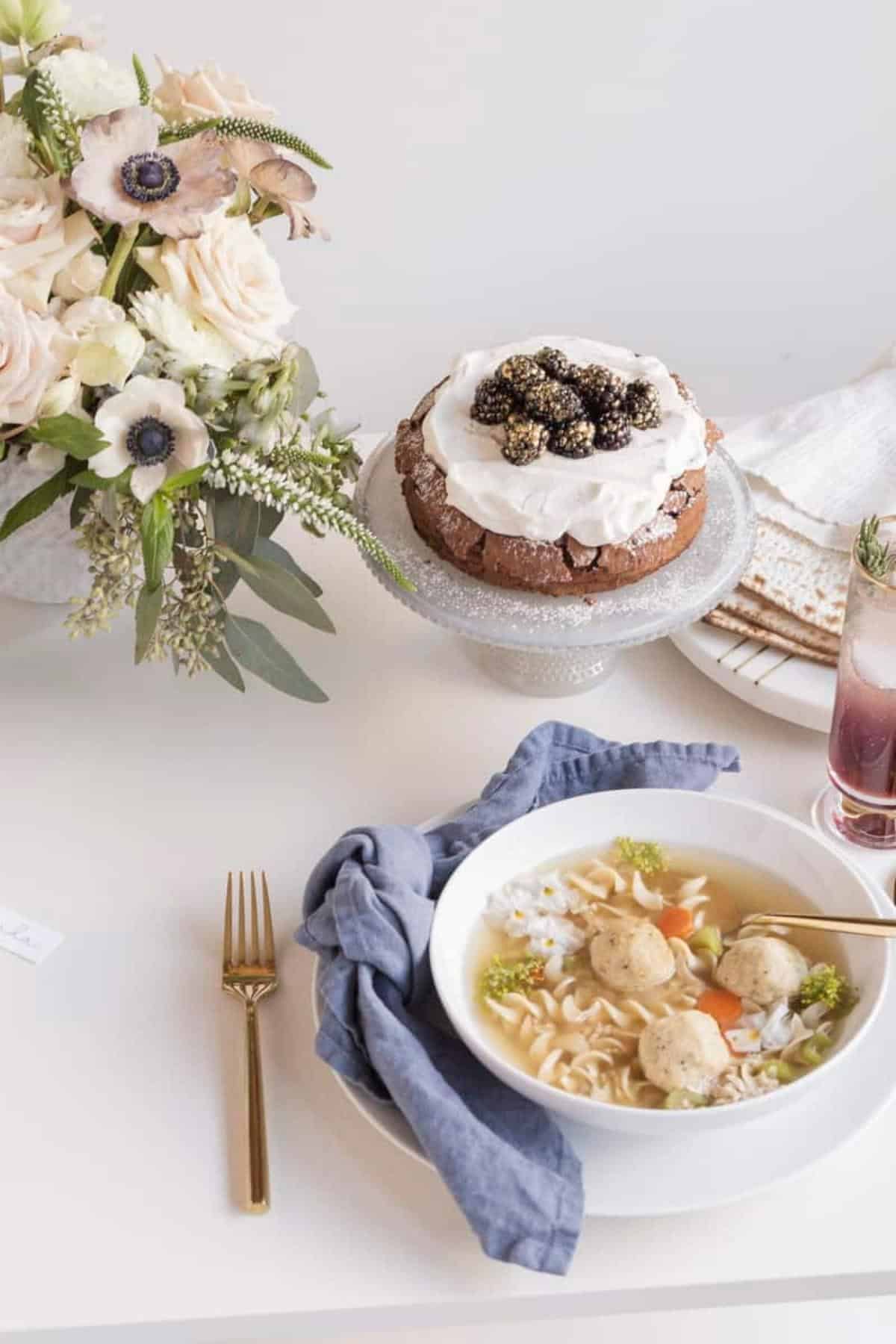 Passover table setting with matzo ball soup and flourless cake