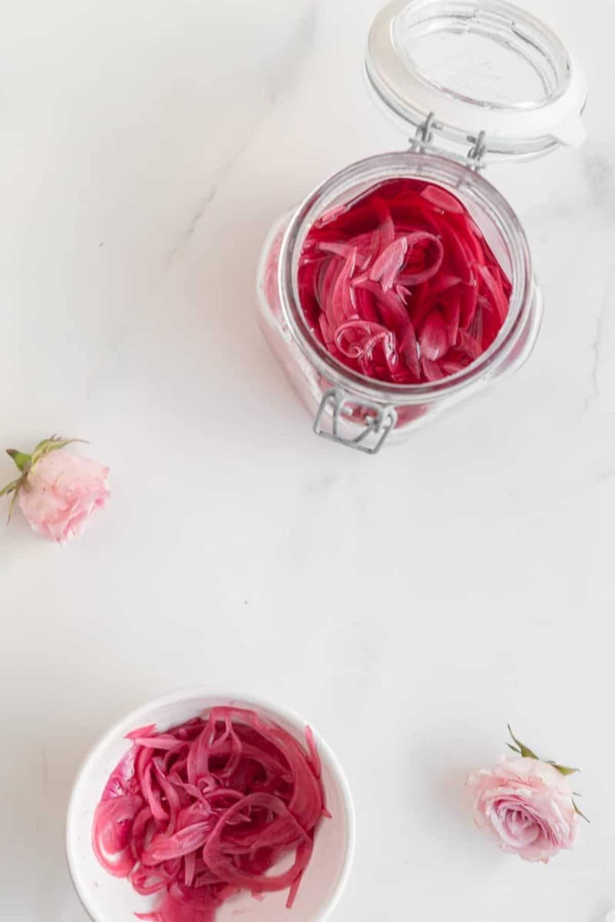 pickled onions in a jar and in a bowl on a marble surface