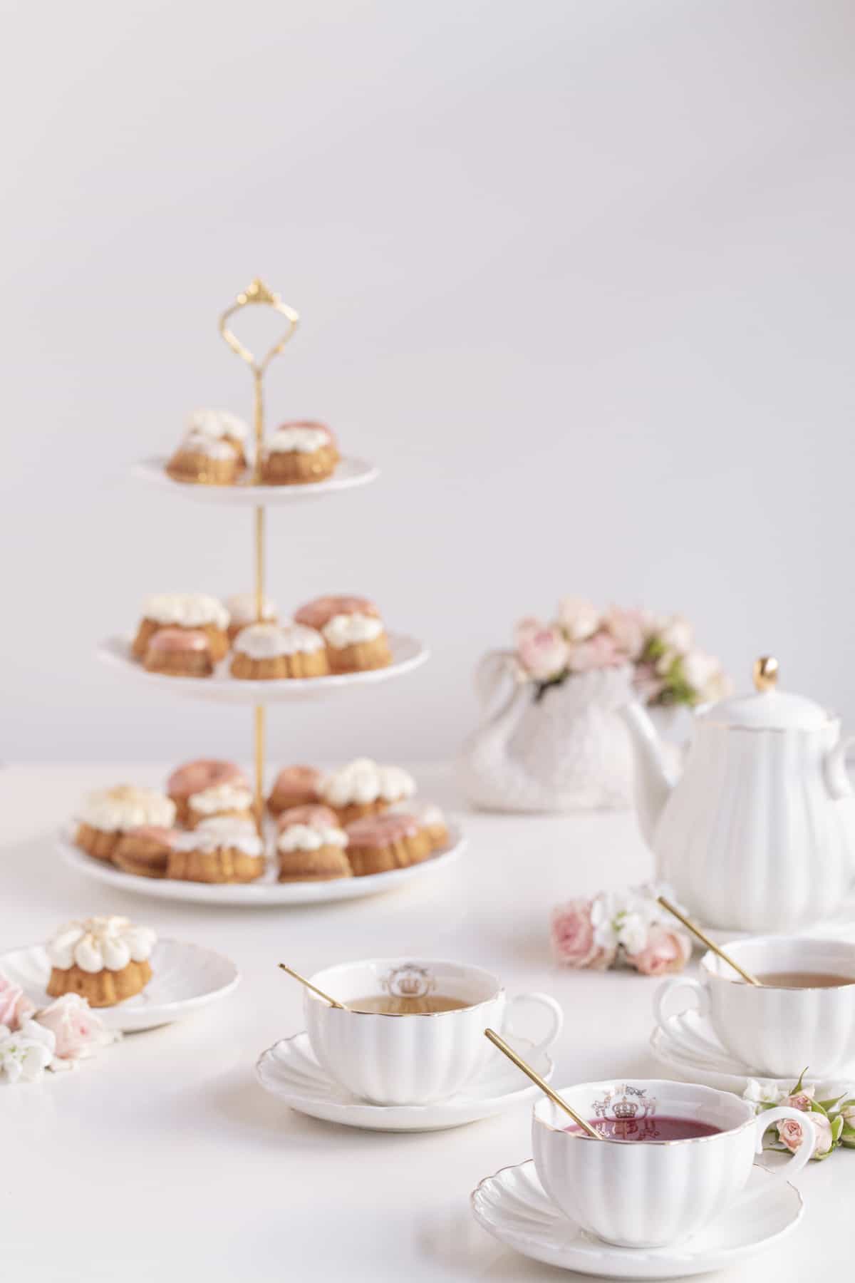 fancy tea cups and saucers with tea cakes and flowers