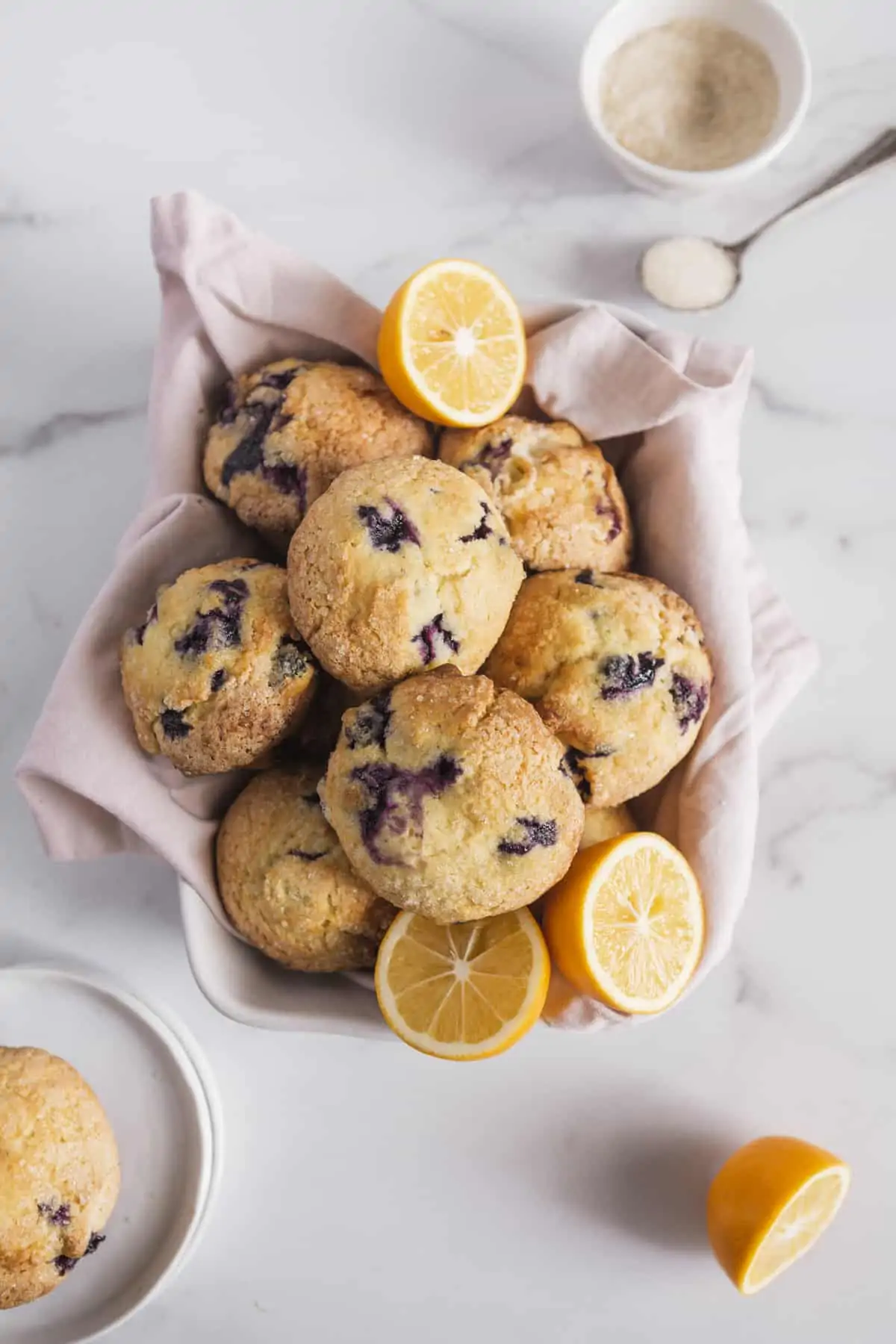 muffins piled into a basket with sugar bowl and lemon to the side