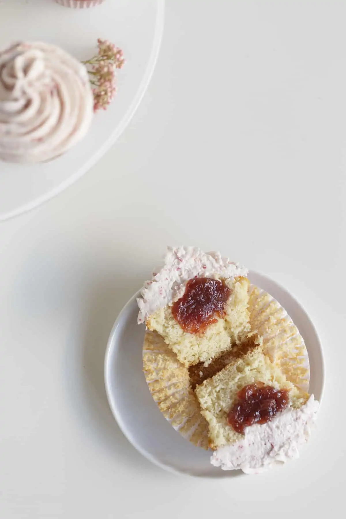 vanilla cupcakes with strawberry filling sliced open to show jam inside