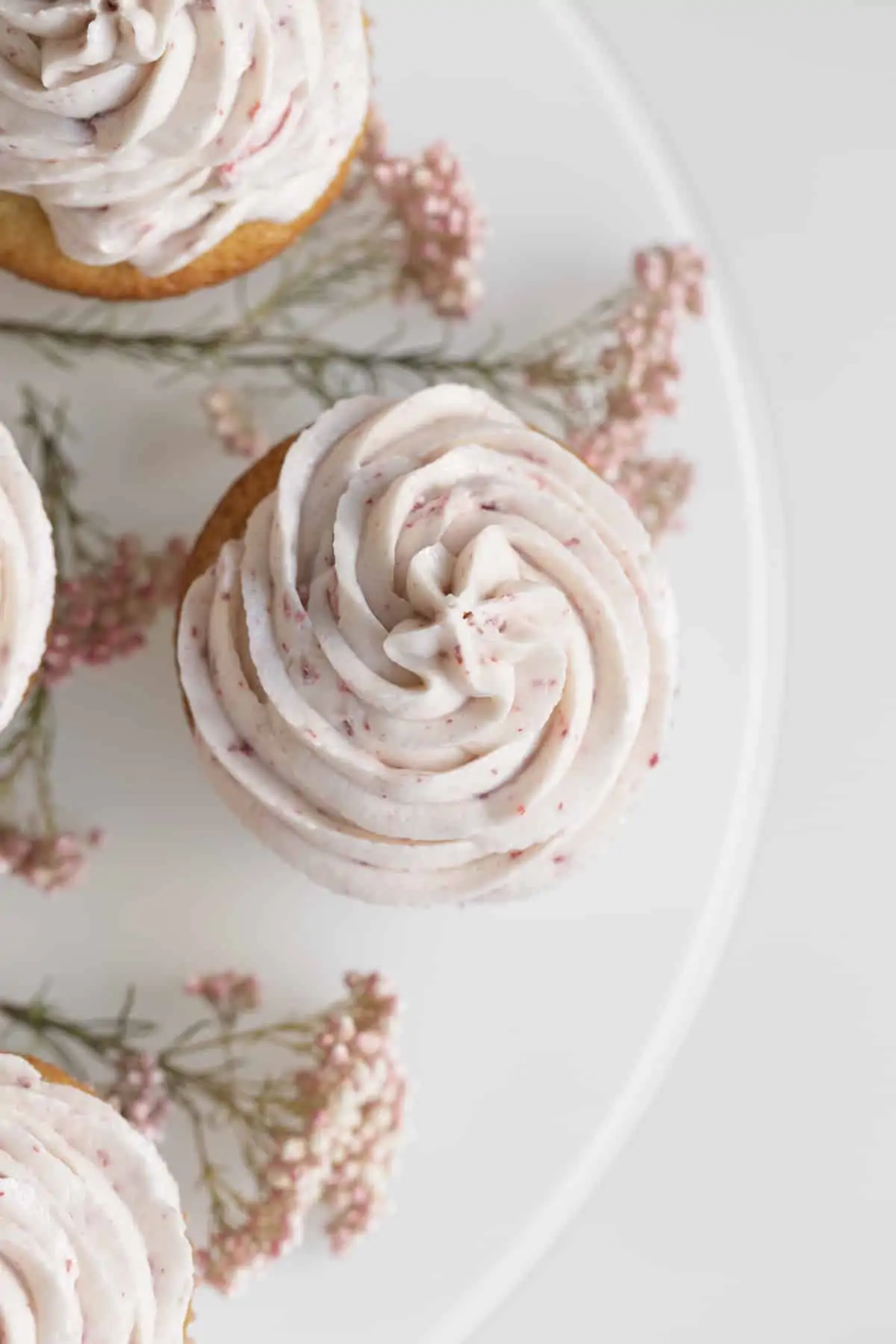 strawberry preserve cupcakes from above with pink frosting and flowers