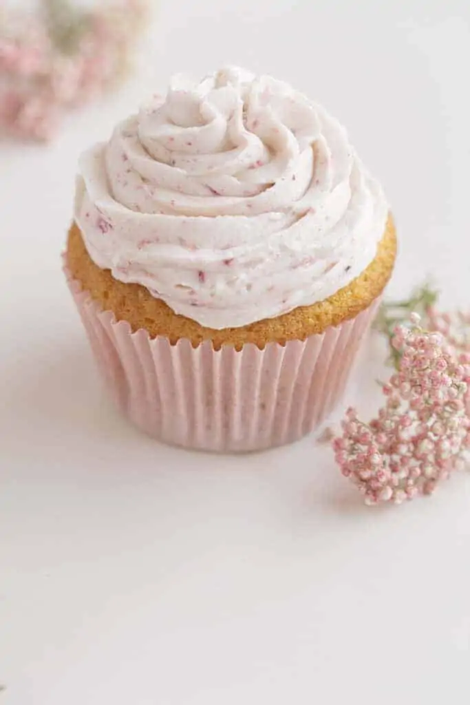 strawberry filled cupcake with pink liner and pink flowers