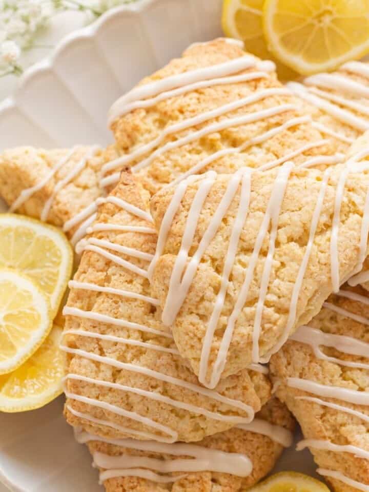 lemon glaze on scones on a plate with lemon slices