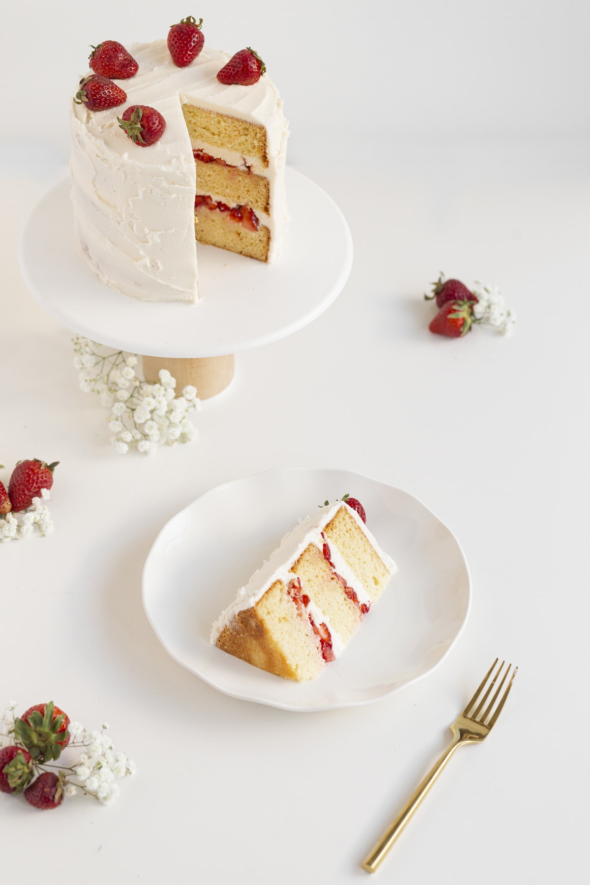 strawberry lemon cake sliced on a plate and cake on a stand