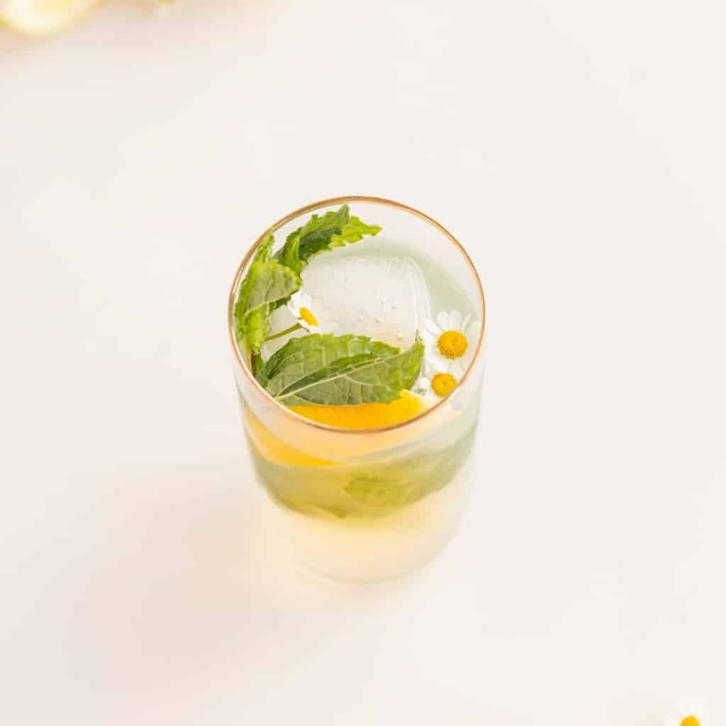 lemon mocktail with flowers, ice, mint, and lemon slices in a glass