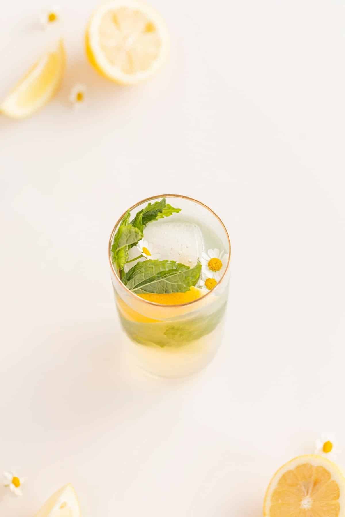 lemon mocktail with flowers, ice, mint, and lemon slices in a glass