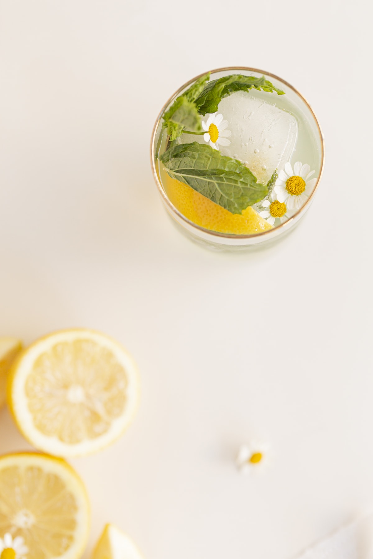 mint lemonade mocktail in a glass with flowers, mint, lemon, ice