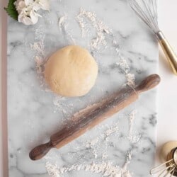 pie dough on a marble surface with flour and rolling pin