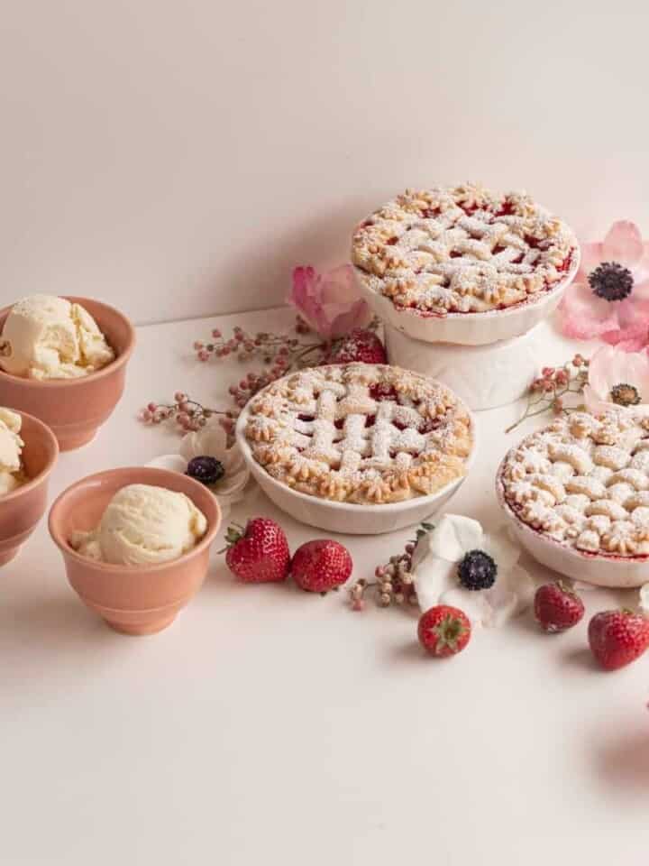 small pies with ice cream with berries and flowers on a white table