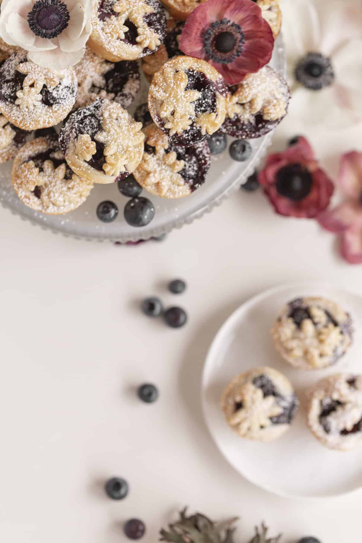 little pies on a cake stand with berries and flowers