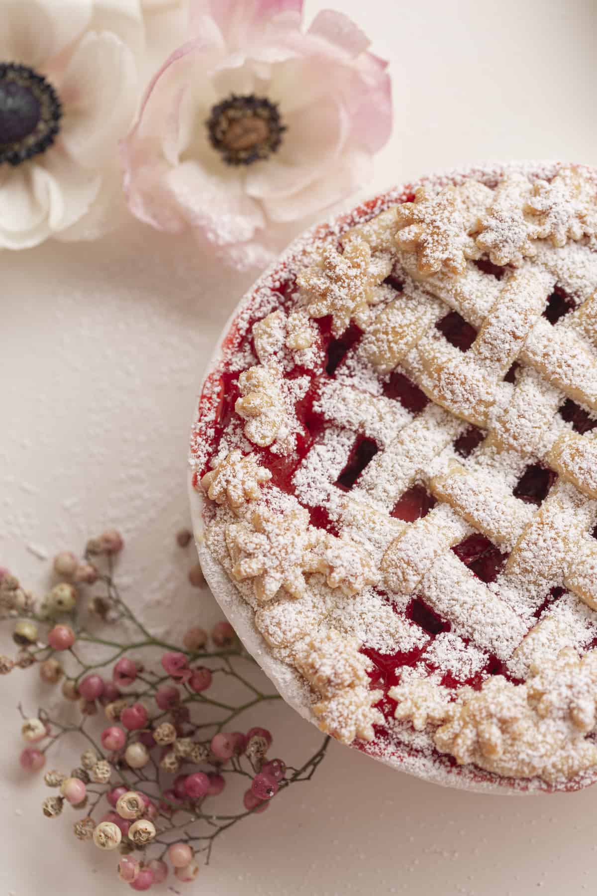 close up of a strawberry pie with lattice top and flowers