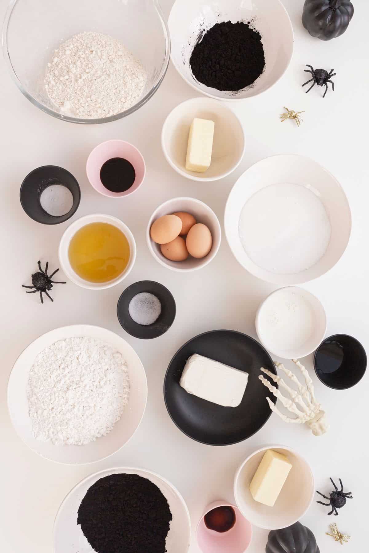 ingredients for black velvet cake in bowls with toy spiders