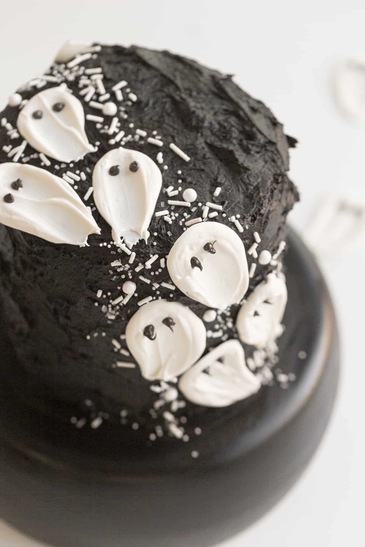 black velvet cake with white candy ghosts on a black cake stand