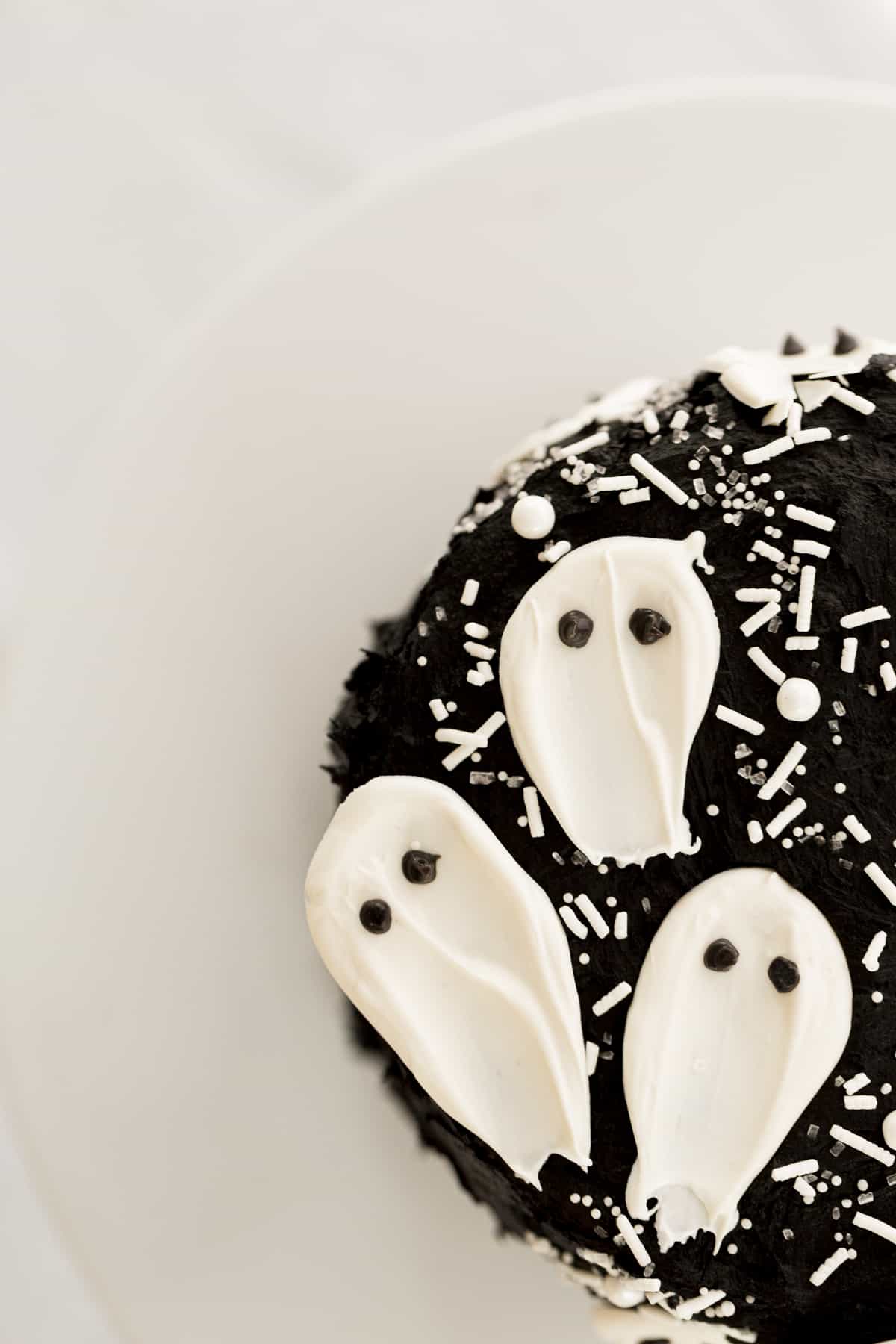 black velvet cake with white candy ghosts on a black cake stand