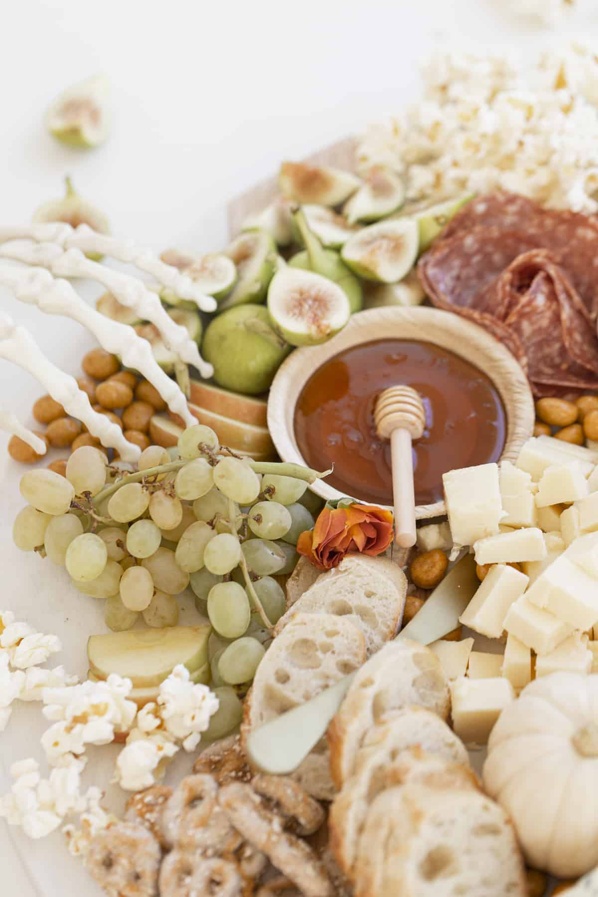 charcuterie board with fruits and knife with a few skeleton fingers