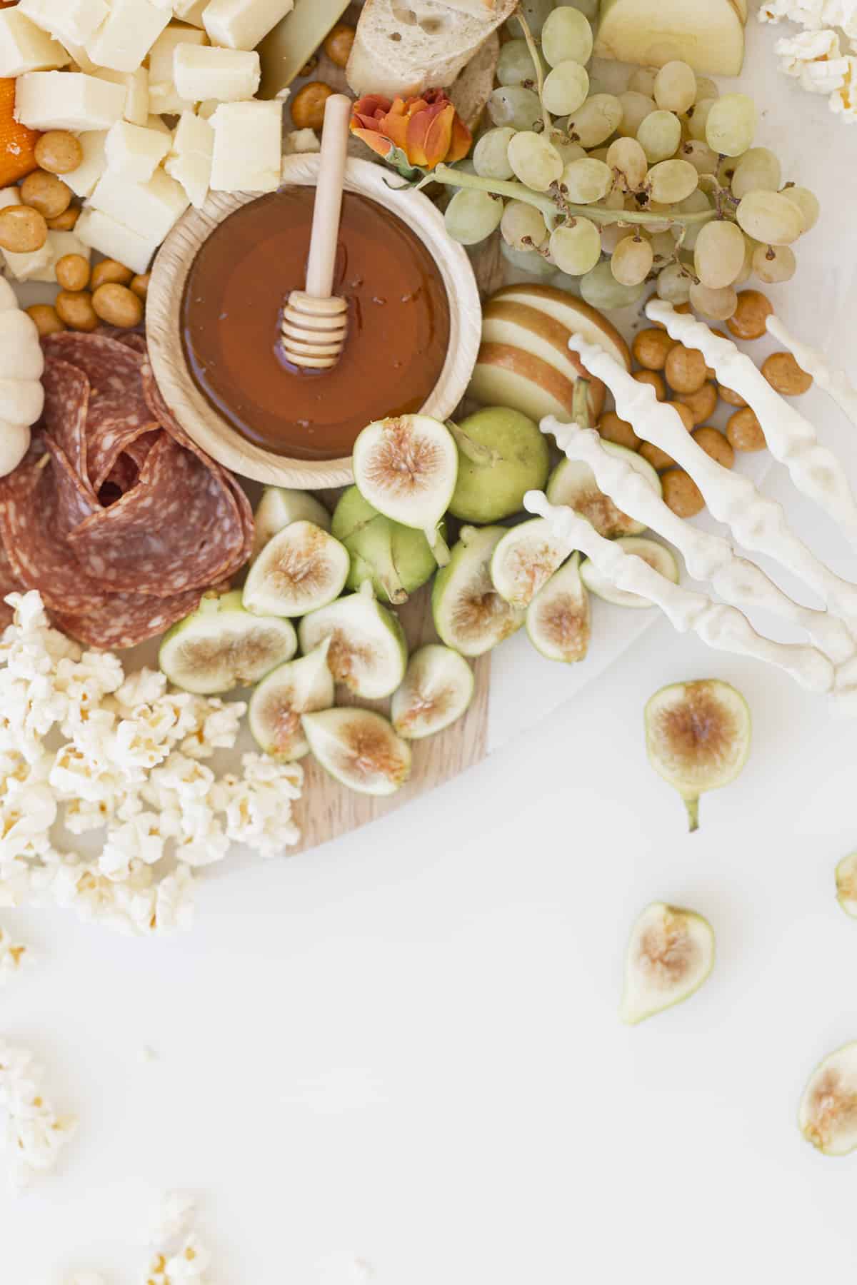 honey fruits and cheese on board with honey dipper and skeleton hand