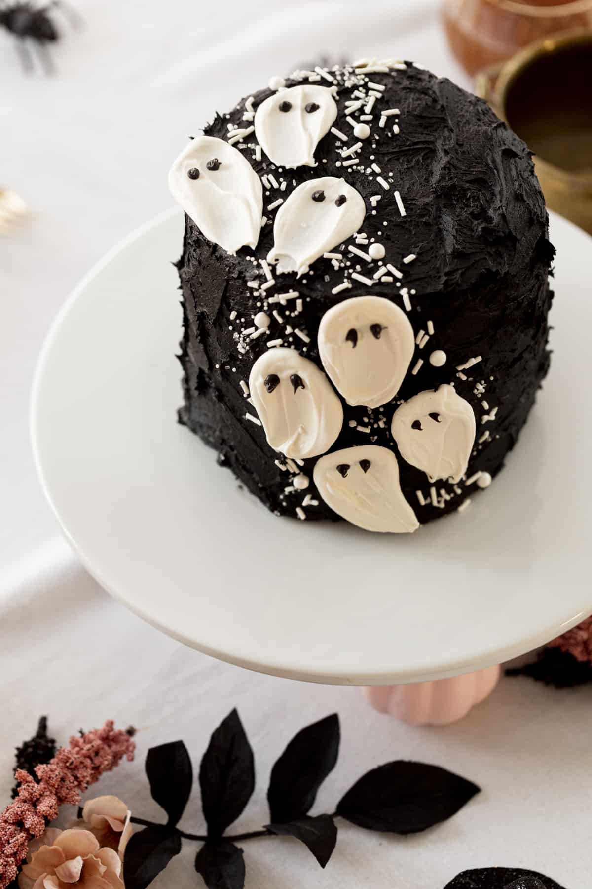 ghost cake on a white cake stand on a halloween table