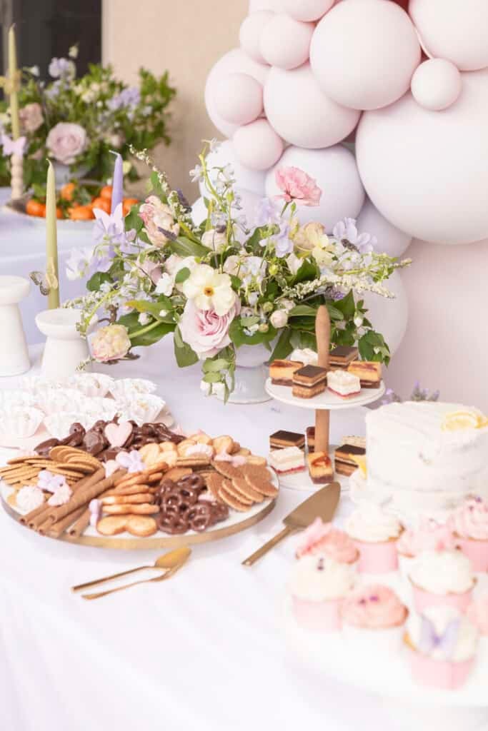 dessert trays on a table with flowers and balloons