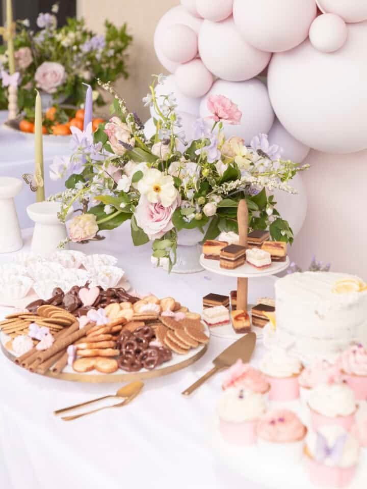 dessert trays on a table with flowers and balloons