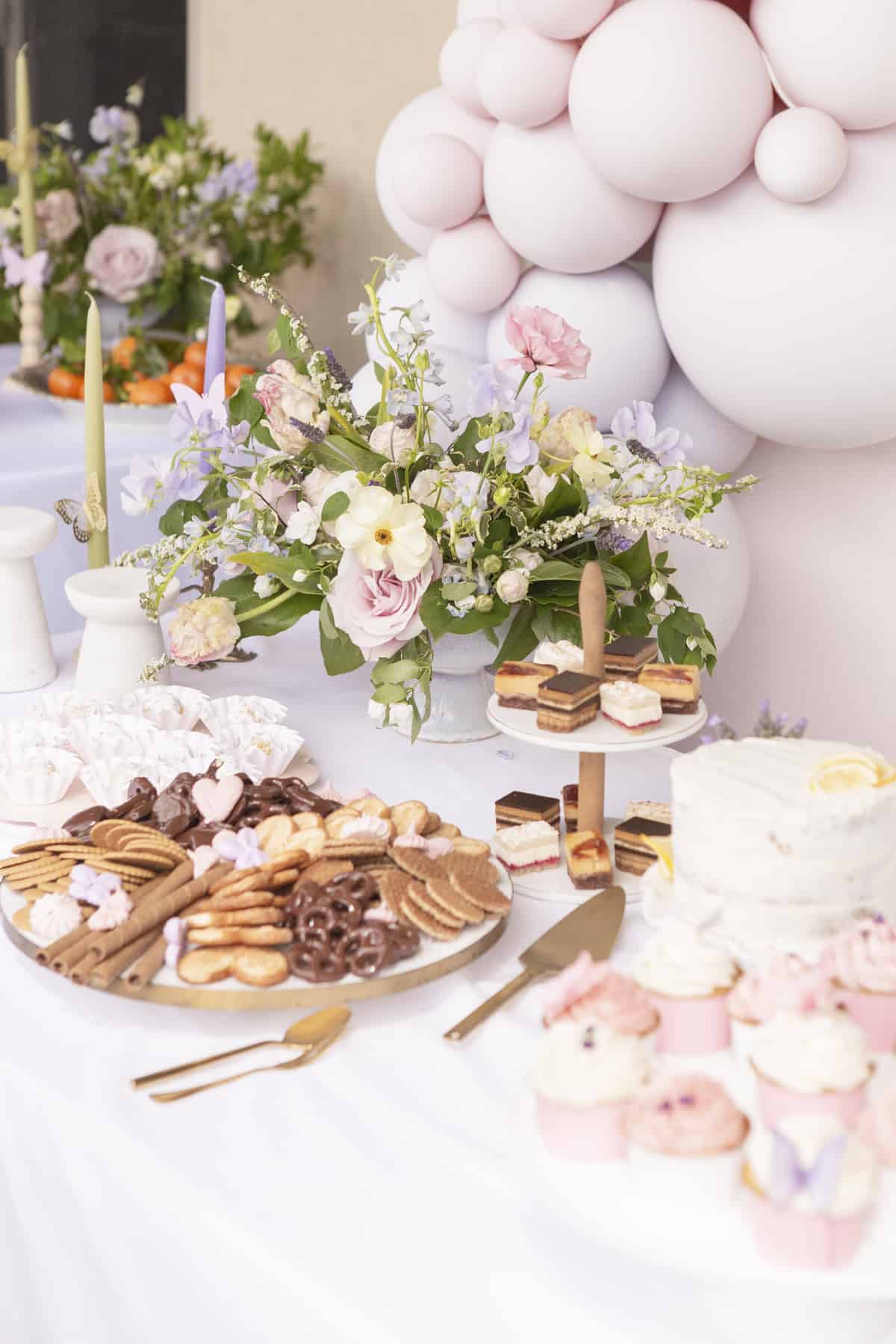 dessert trays on a table with flowers and balloons