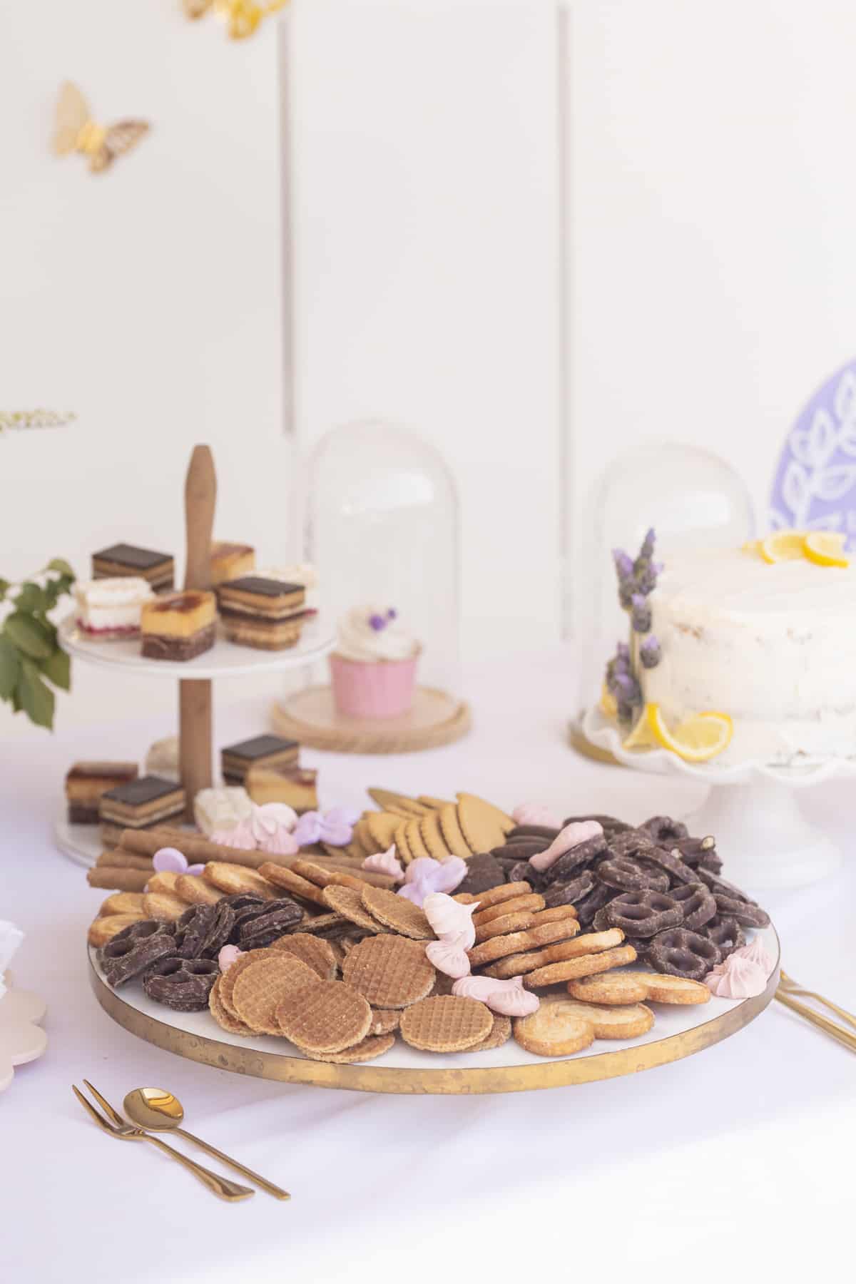 dessert board on a white table with cupcakes and cake in the background