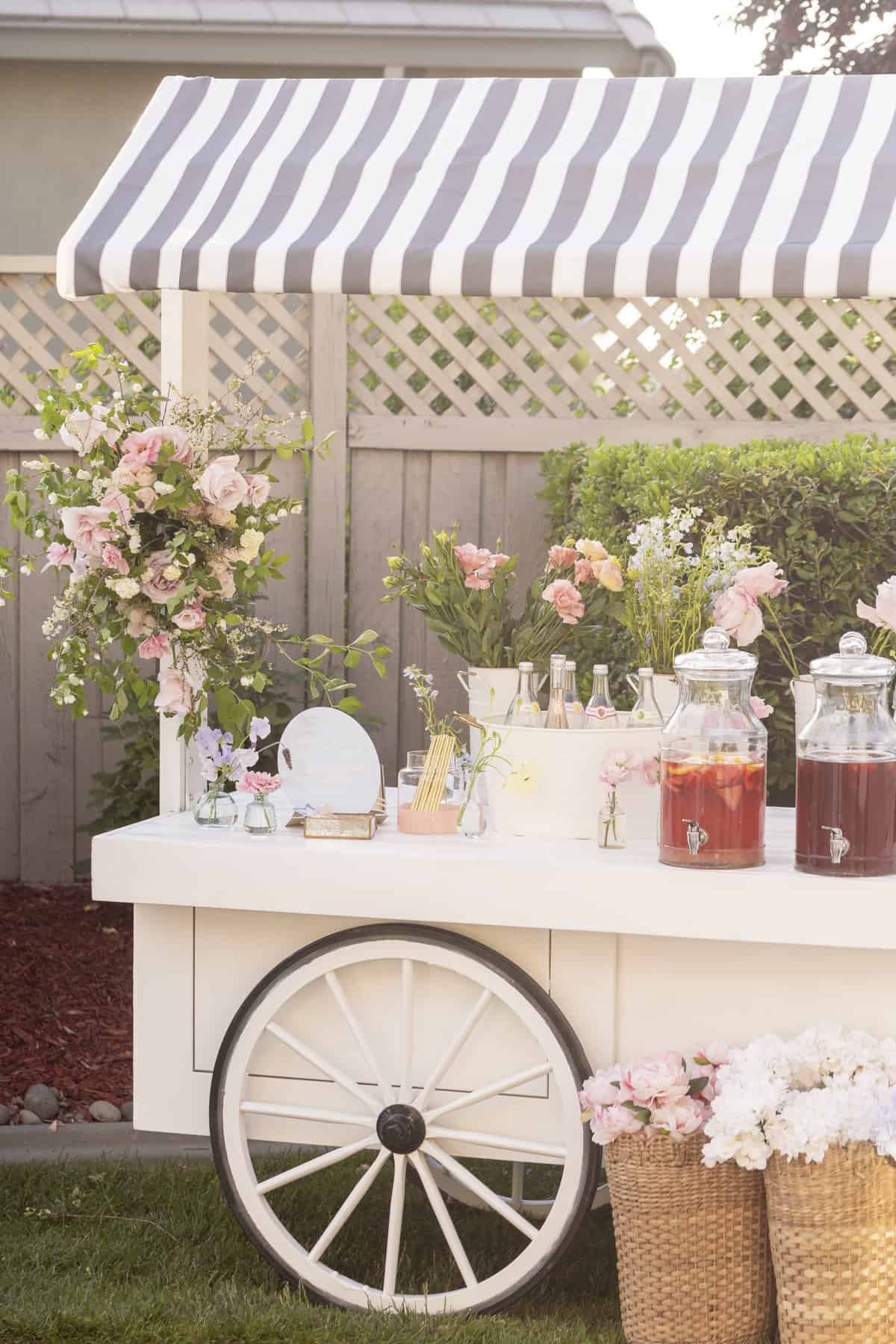 white cart with big wheel and flowers on it holding drink despensers