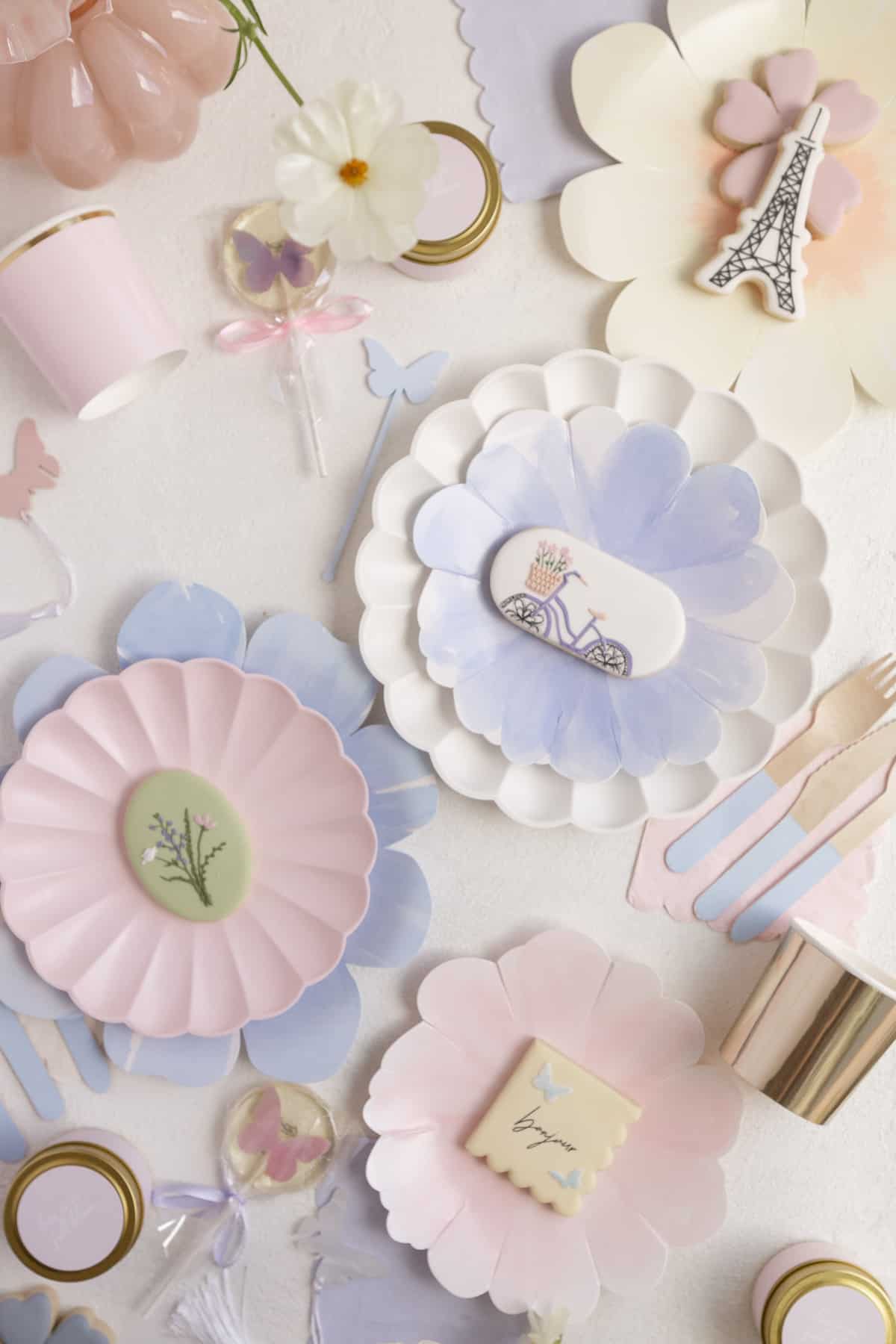 paper flower plates with cookies and lolliepops and candles on a flatlay